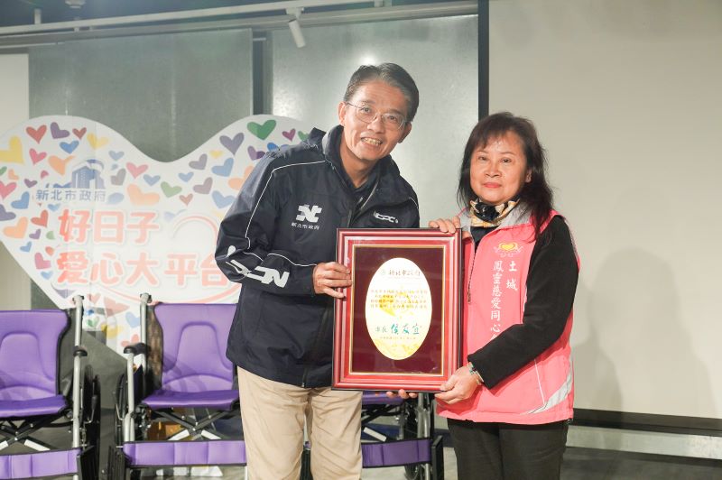 《圖說》新北市府秘書長邱敬斌(左)代表侯友宜市長回贈感謝牌給土城鳳靈慈愛同心會理事長黃妙鳳。〈社會局提供〉